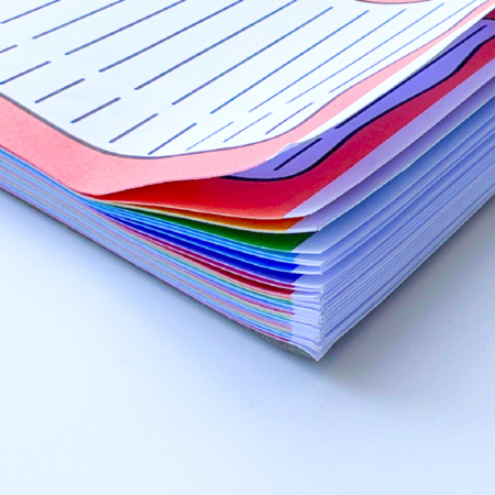 Close-up of the A5 Rainbow Priority Task List, showing a stack of colourful lined sheets—pink, blue, green, and white pages—slightly fanned out on a white surface.