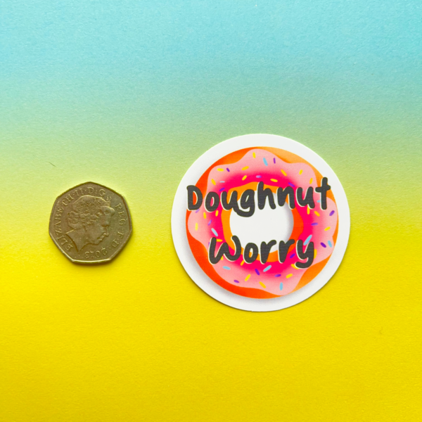 The Doughnut Matt Vinyl Sticker 1 showcases a pink iced doughnut and “Doughnut Worry” text beside a British 50p coin, on a blue and yellow gradient background.