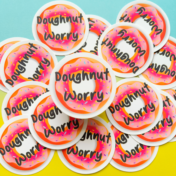 The Doughnut Matt Vinyl Sticker 3 features a round pink frosted doughnut with sprinkles and "Doughnut Worry" in playful black letters, set on a cheerful blue and yellow background.