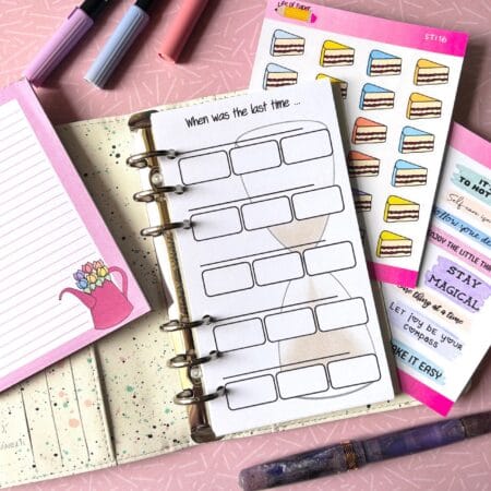 A personal ring planner is open on a table.The top sheet says 'Last time I…' and has a sandtimer drawn in the background. The sheet then has a line to say what job it is and then boxes for the dates. There is space for several jobs on one side. The picture has a pink background. Around the planner are brush pens, sticker sheets, a pink memo pad and a fountain pen. 