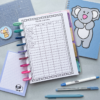 Monthly Budget Planner Insert 2 with colourful pens, a sheep notepad, a blue koala folder, and a dog sticker are neatly arranged on a light grey surface.