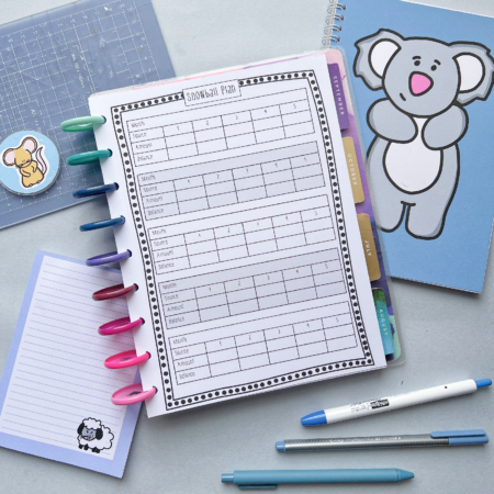 The Snowball Debt Repayment Pages 5 are displayed in a colourful folder on a desk alongside animal design notebooks, a sheep notepad, pens, and a transparent ruler.