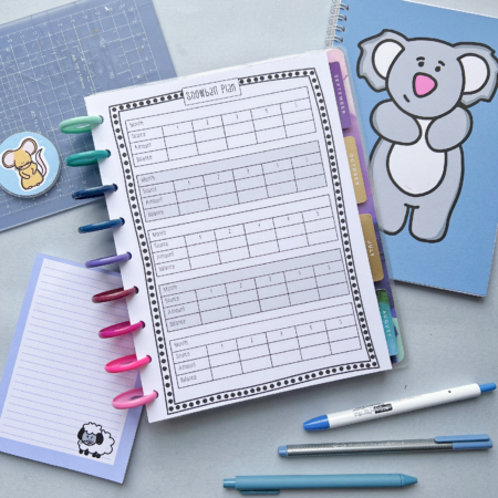 A desk with Snowball Debt Repayment Pages 6 in a binder, surrounded by colourful pens, a blue koala notebook, a small sheep notepad, and a bear sticker.
