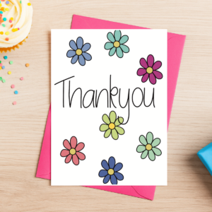 The Thank You Flowers Card 4 features vibrant blooms and bold "Thank you" text, set on a pink envelope with a wooden table background, surrounded by a cupcake and cheerful confetti.