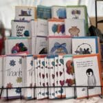 A tiered card stand in black with rows of greeting cards stood up on display.